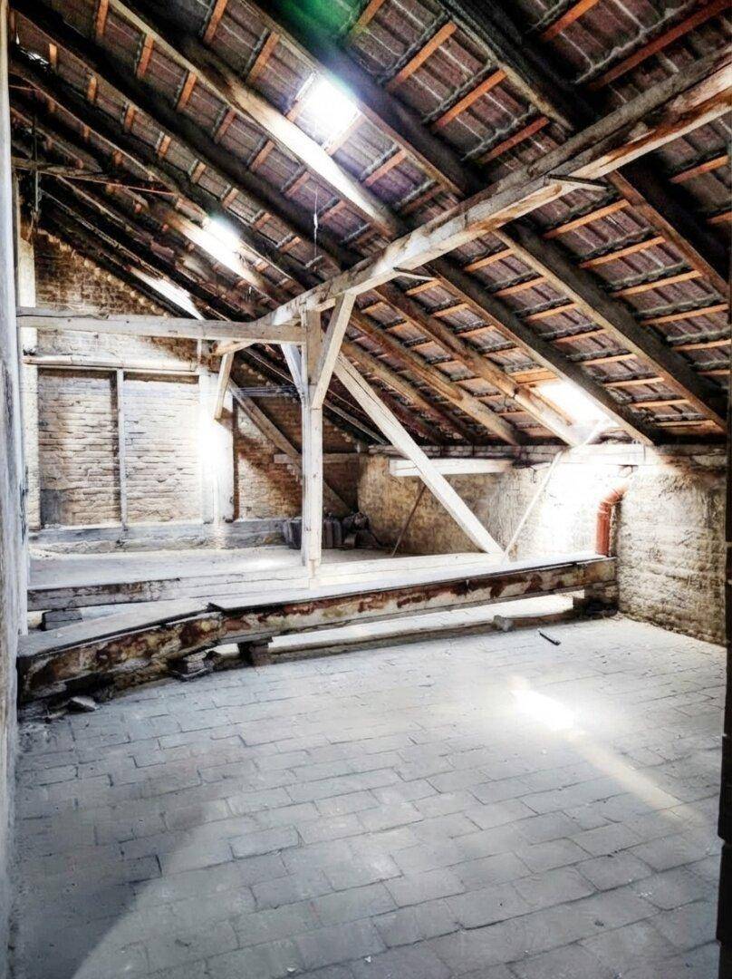Geräumiger Dachboden mit freiliegenden Holzbalken und Ziegelwänden, ideal für einen zukünftigen Ausbau.