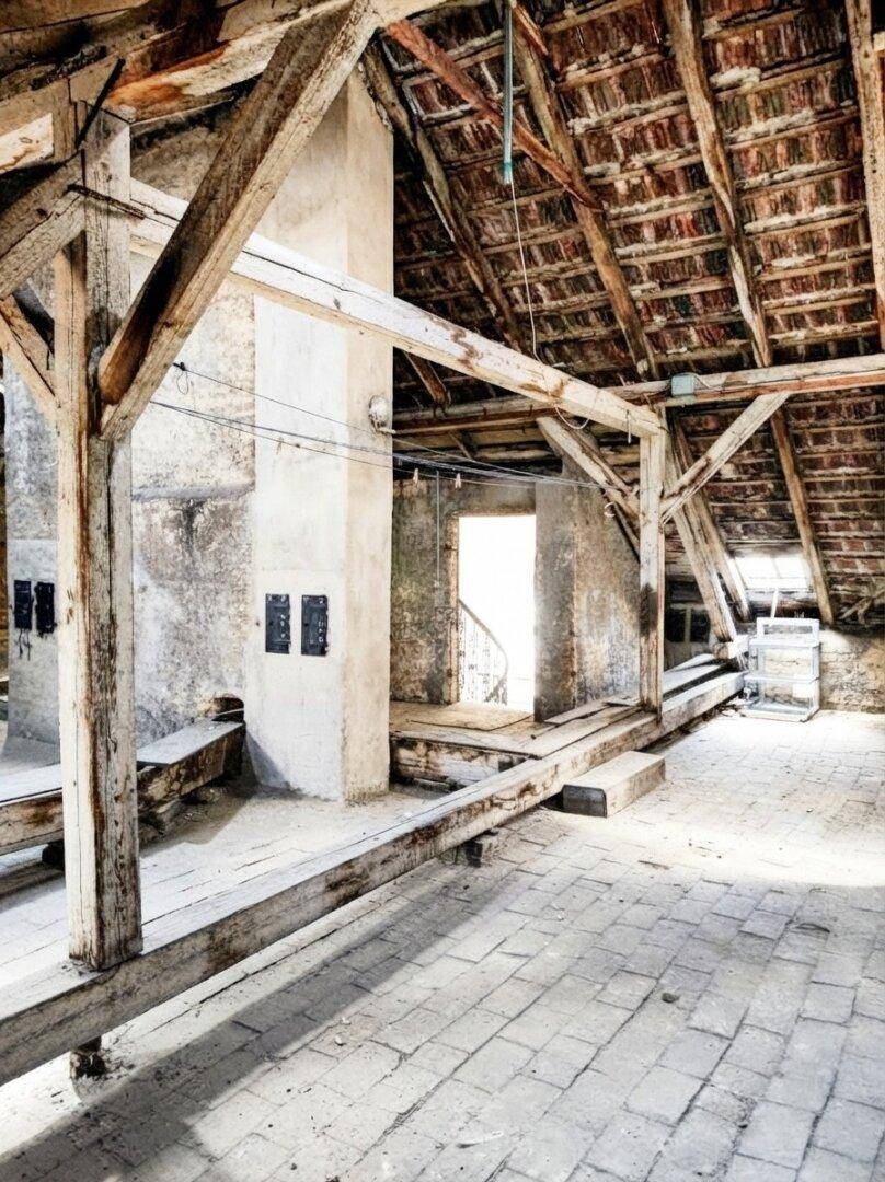 Heller Dachboden mit freiliegenden Holzbalken und viel Tageslicht, perfekt für den Ausbau.