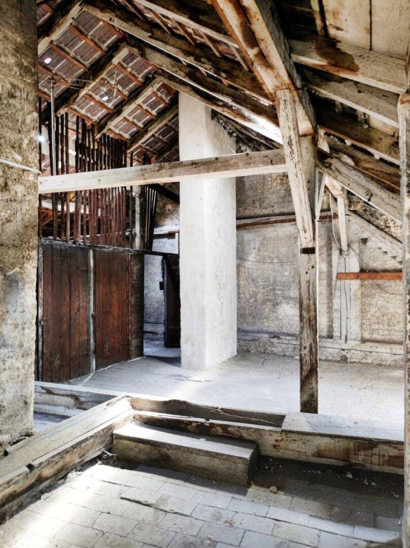 Geräumiger Dachboden mit sichtbaren Holzbalken und Ziegeln, bereit für den Ausbau.