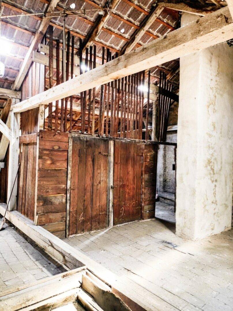 Unausgebauter Dachboden mit rustikalen Holzwänden und sichtbarer Dachkonstruktion, hell.