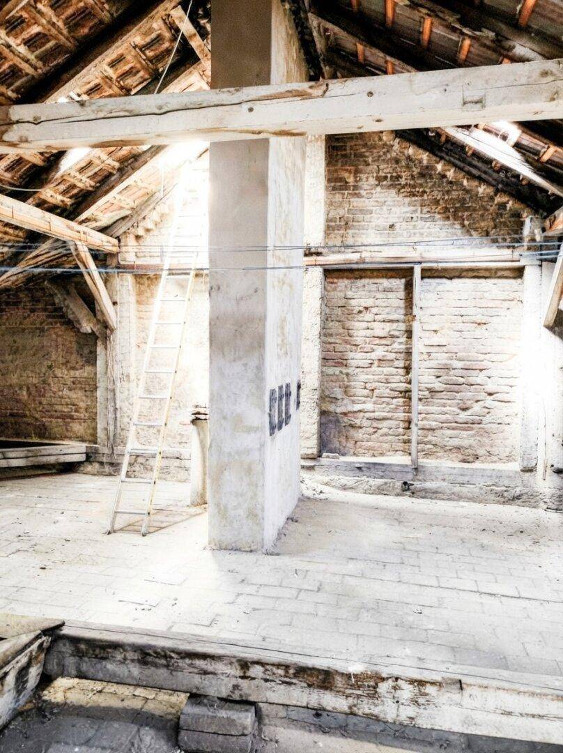 Dachboden mit Leiter und freigelegten Ziegelwänden, bereit für den Ausbau und Umgestaltung.