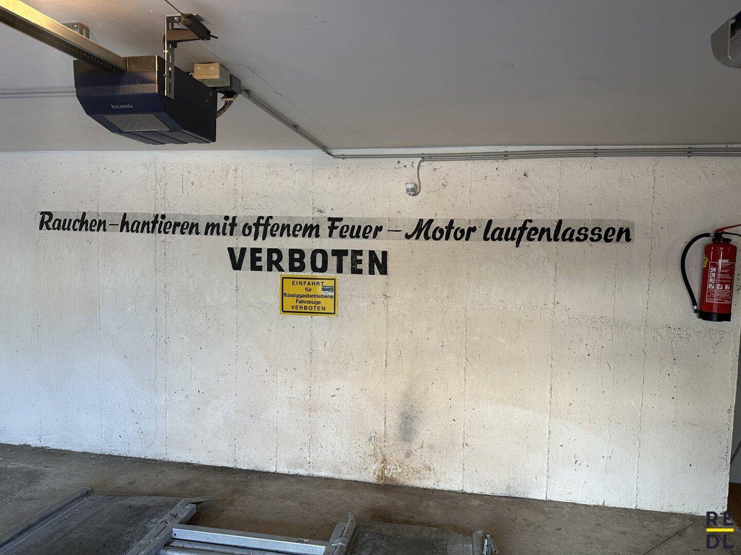 Innenansicht der Tiefgarage mit großem Warnhinweis zu Rauchen und Motorlaufenlassen.