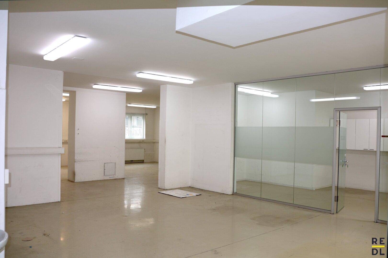 Geräumiges, leeres Büro mit Glasabtrennungen und Blick in weitere Arbeitsbereiche.