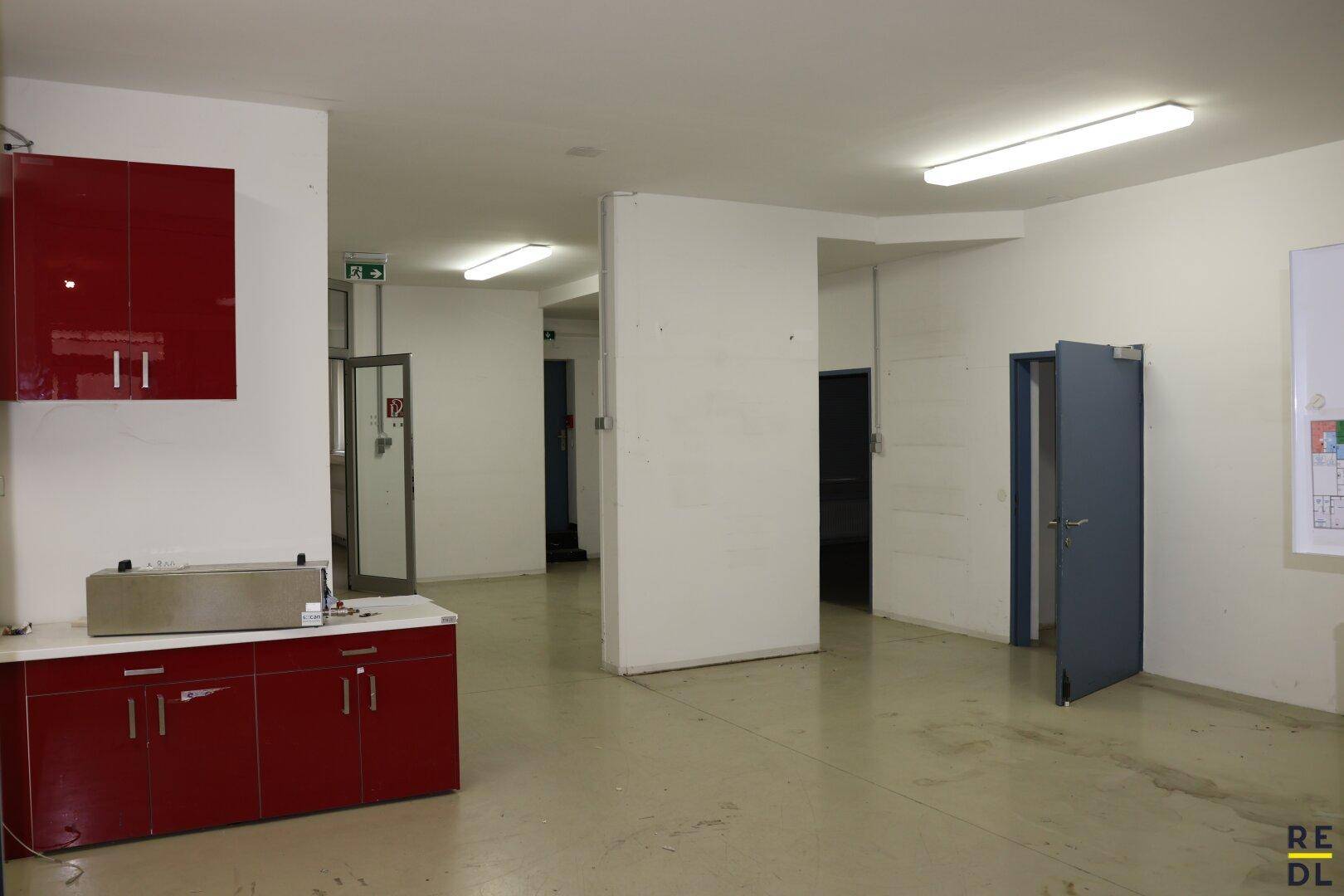 Flur oder Gemeinschaftsbereich mit roten Küchenschränken und Zugang zu weiteren Räumen.