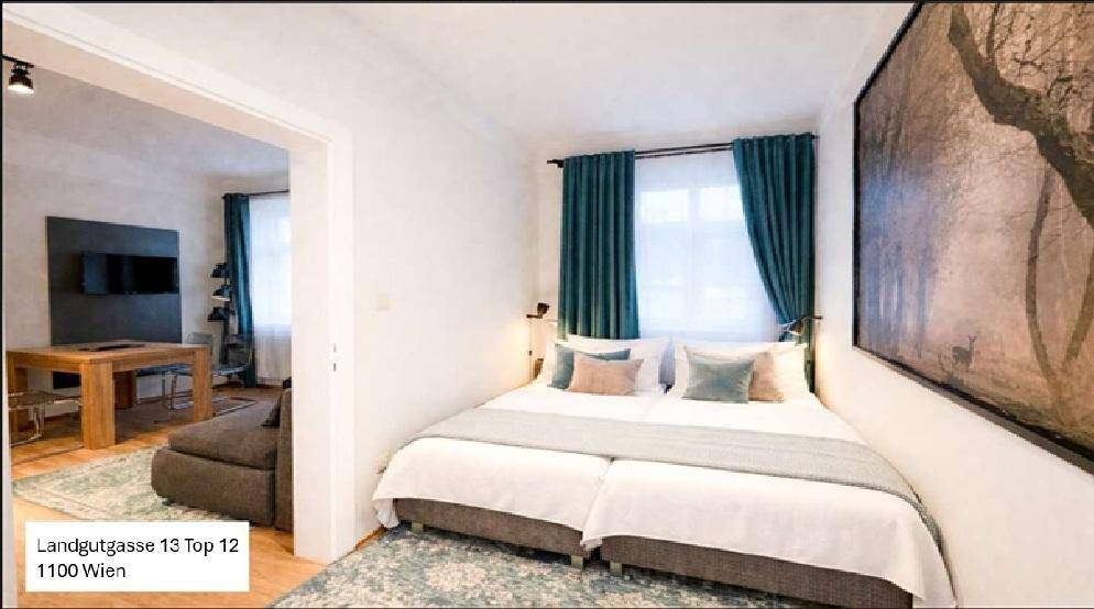 Gemütlicher Schlafbereich in einem Studio-Apartment mit Doppelbett und dekorativen Kissen.
