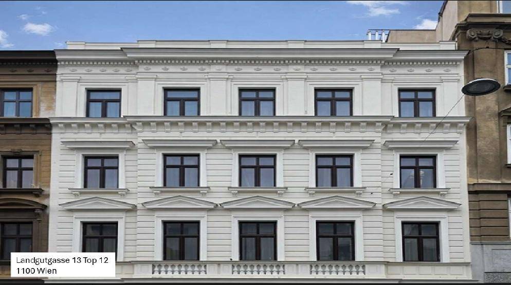 Symmetrische Fassade eines Altbaus in Wien mit dekorativen Elementen und vielen Fenstern.