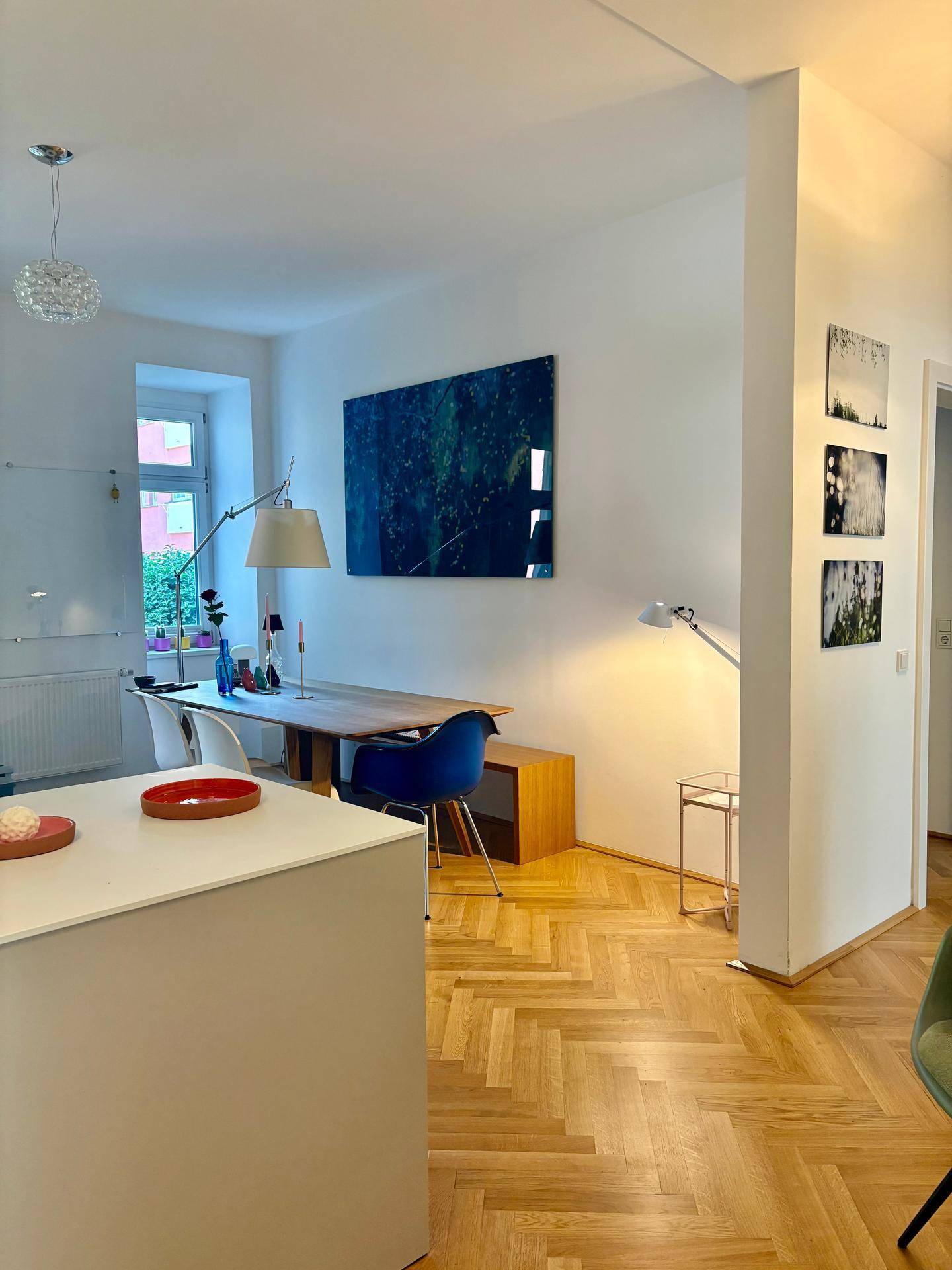 Helles, offenes Wohn- und Esszimmer mit Fischgrätparkett und moderner Kunst an der Wand.