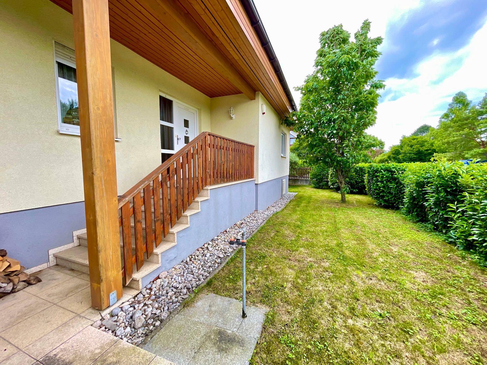 Eingangsbereich des Hauses mit Holzgeländer und seitlichem Zugang zum Garten.