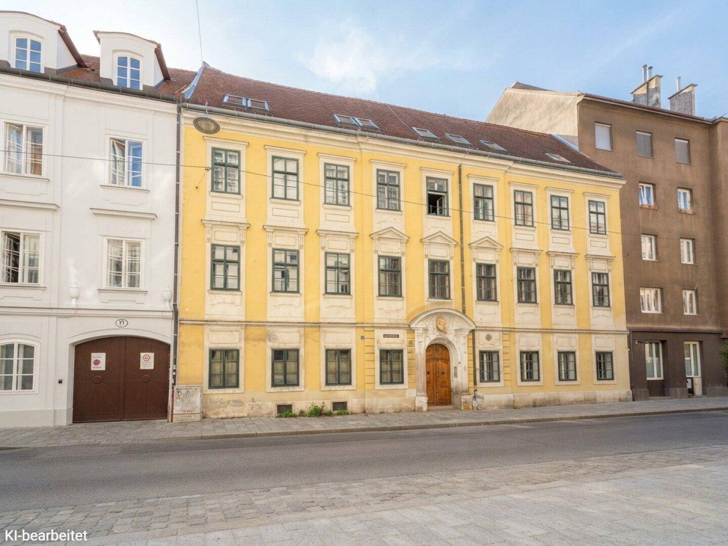 Historische gelbe Fassade eines Gebäudes mit vielen Fenstern und klassischer Architektur.