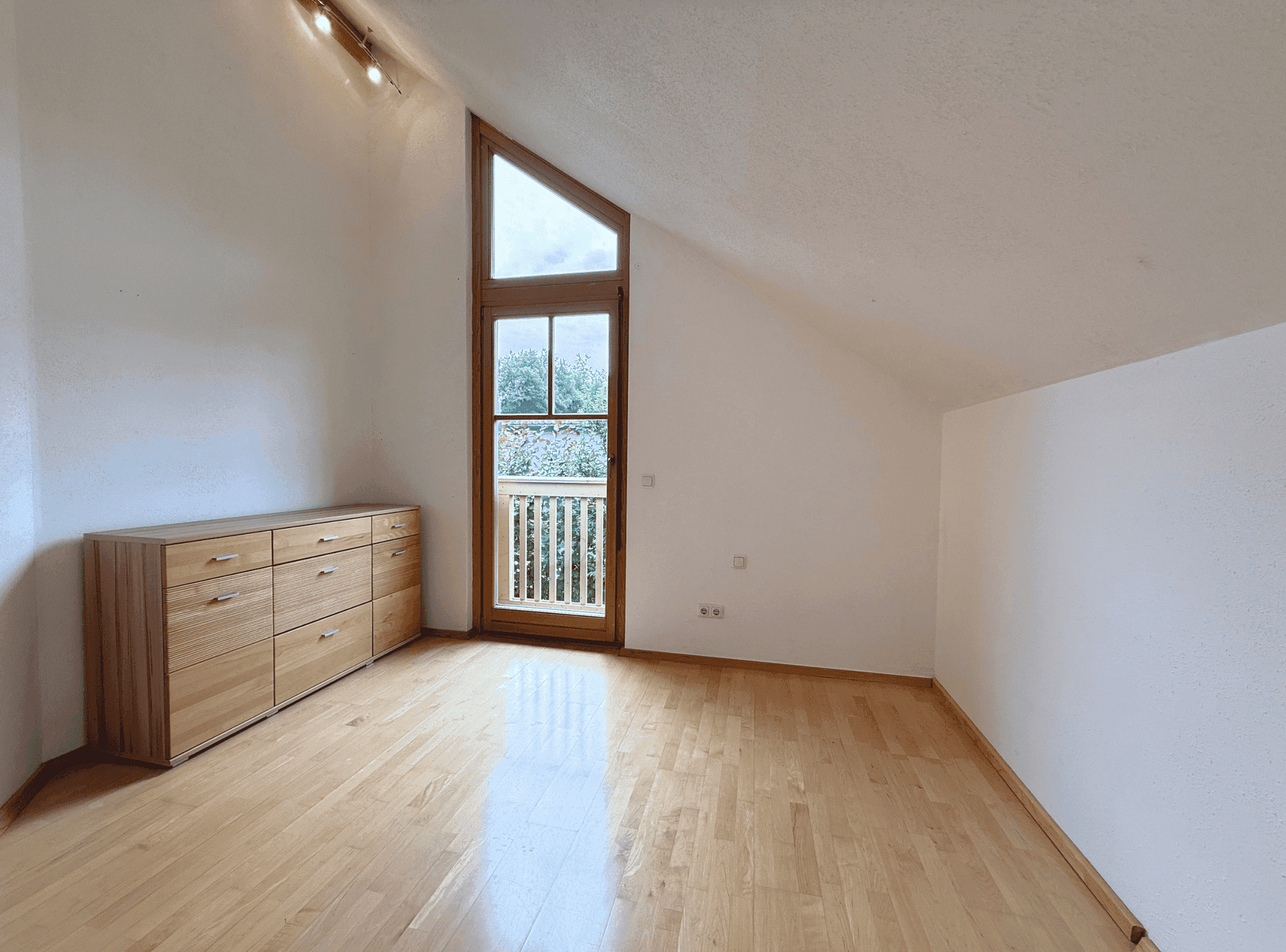 Helles Schlafzimmer im Dachgeschoss mit Holzboden, Dachschräge und französischem Balkon.