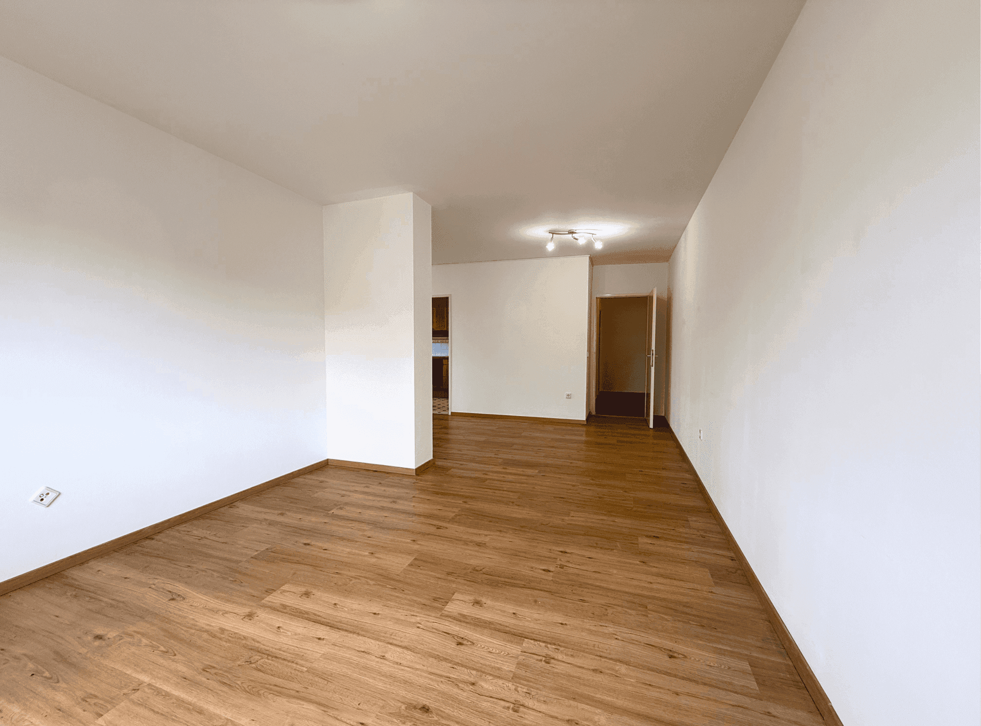 Heller Wohnbereich mit Laminatboden und weiß gestrichenen Wänden, bietet vielseitige Nutzungsmöglichkeiten.