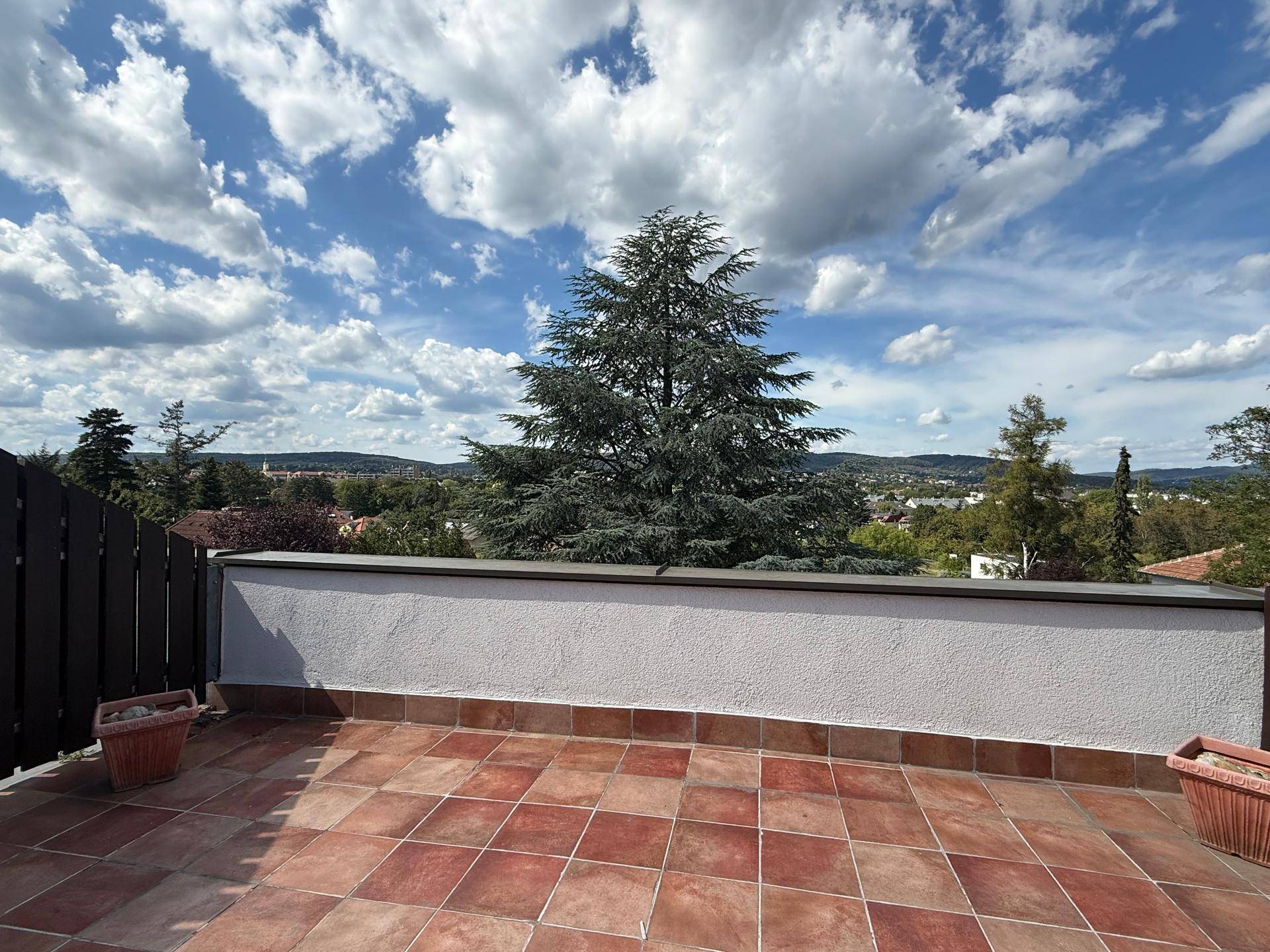 Große geflieste Terrasse mit weitem Blick über die Landschaft und bewölktem Himmel.