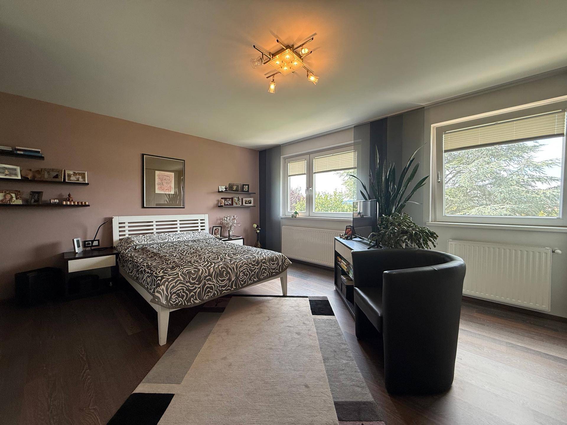 Gemütliches Schlafzimmer mit Doppelbett, dunklem Holzboden und großen Fenstern.