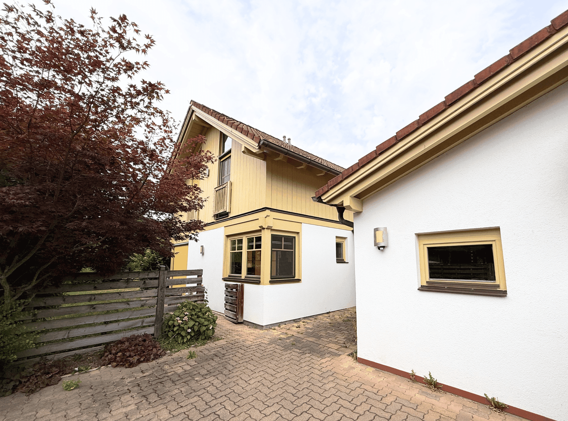 Gesamtansicht des Hauses und Nebengebäudes mit gepflasterter Zufahrt.