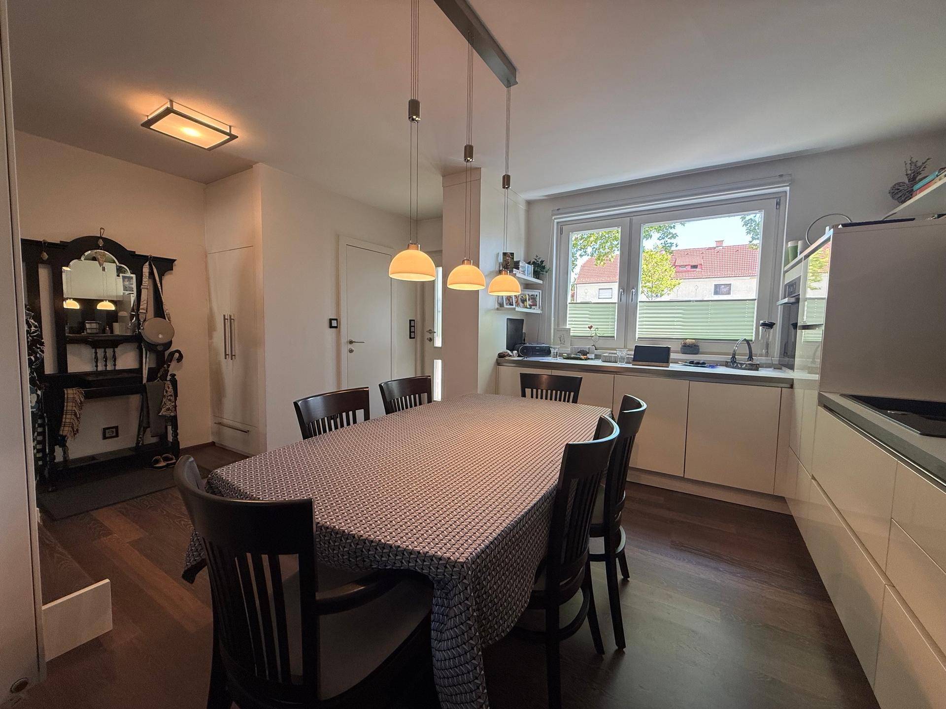 Funktionale Küche mit Essbereich, Fenster und Garderobe im Eingangsbereich.