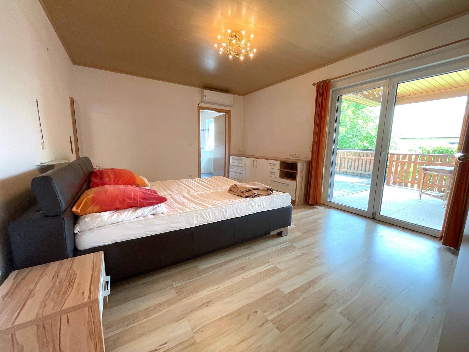 Schlafzimmer mit Doppelbett, Laminatboden und direktem Zugang zu einem Balkon.