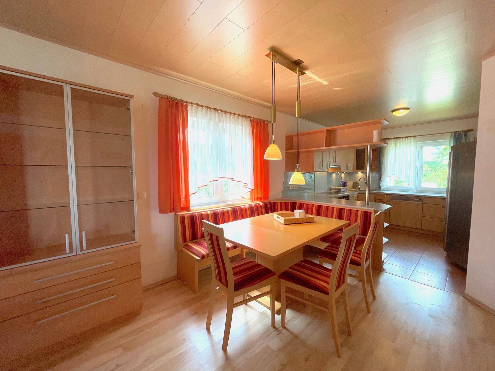 Gemütlicher Essbereich mit Holztisch und Sitzbank, offen zur Küche, mit viel Tageslicht.