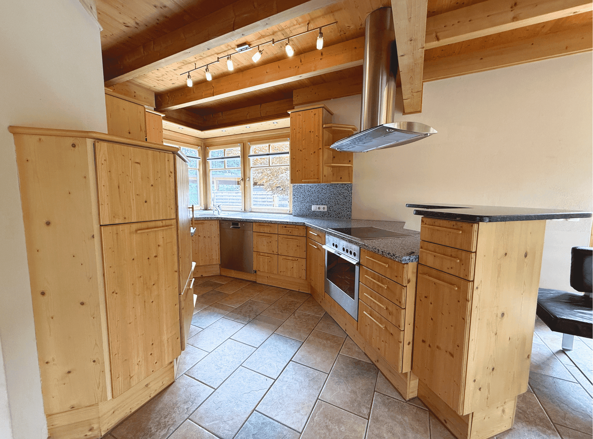 Rustikale Küche mit Holzschränken, Granitarbeitsplatten und sichtbaren Holzdeckenbalken.