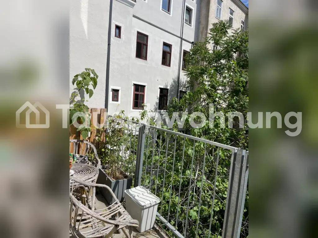 Kleiner Balkon mit Sitzgelegenheiten und Blick auf die umliegenden Gebäude und Bäume.