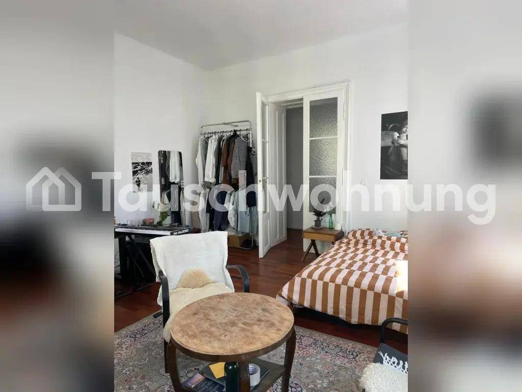 Schlafzimmer mit Doppelbett, Kleiderständer und Zugang zu einem weiteren Raum.