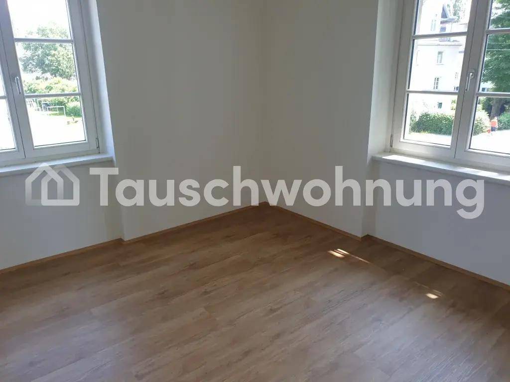 Heller Eckraum mit zwei Fenstern, die viel Tageslicht hereinlassen, und Laminatboden.