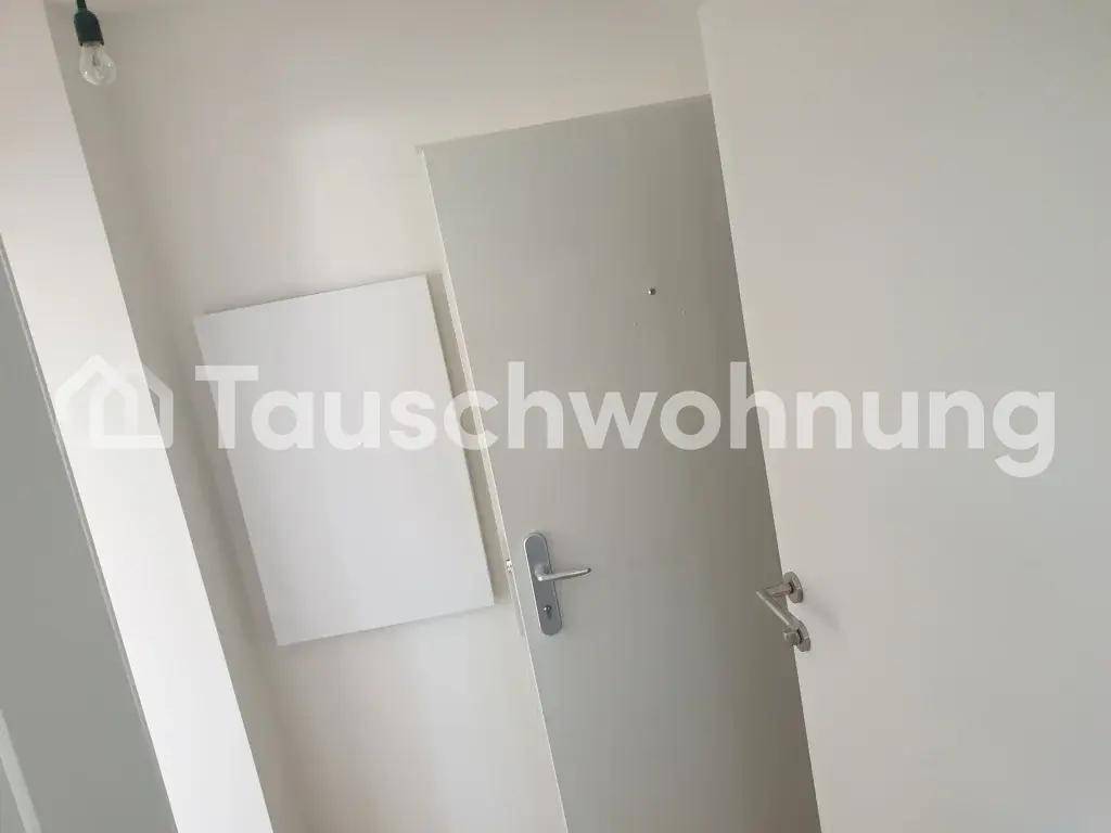 Heller Flur mit weiß gestrichenen Wänden und einer modernen Eingangstür.