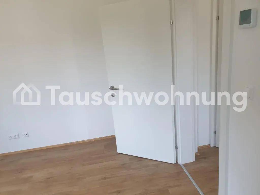 Leerer Raum mit hellen Wänden, Holzboden und einer weißen Tür.