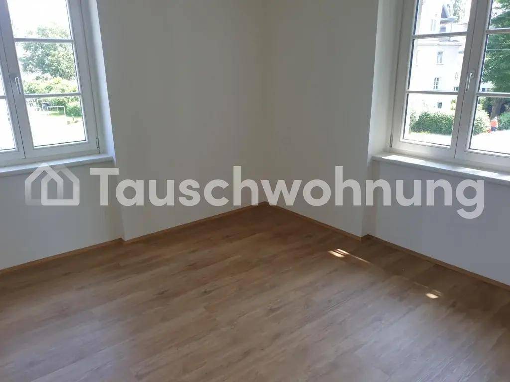 Heller, leerer Raum mit zwei Fenstern und Holzboden, bereit zur Einrichtung.
