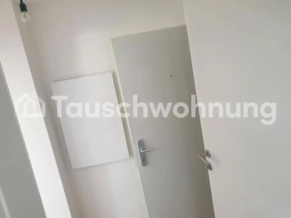 Helle Eingangstür in einem schlichten Flur mit weißen Wänden.