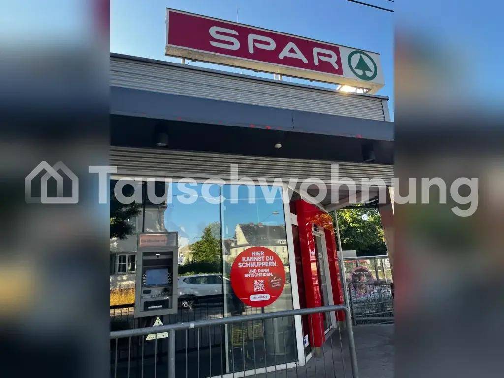 Eingangsbereich des SPAR Supermarktes mit Geldautomat und Werbeschildern.