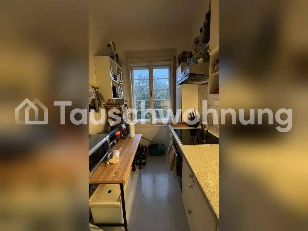 Schmale Küche mit Fenster, Einbaugeräten und einer Arbeitsplatte aus hellem Holz.