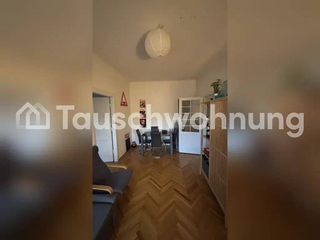 Offener Wohn-Essbereich mit Sofa, Esstisch und klassischem Fischgrätparkettboden.