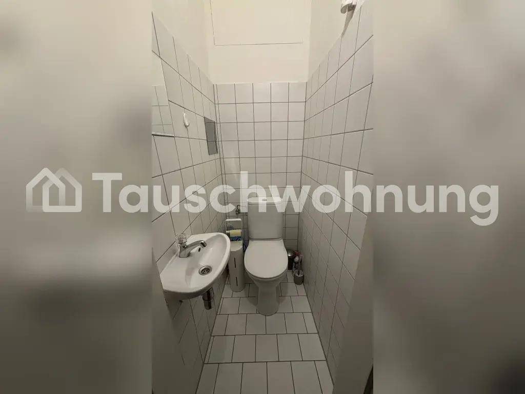 Kleines WC mit wandmontiertem Waschbecken und Toilette, komplett gefliest.