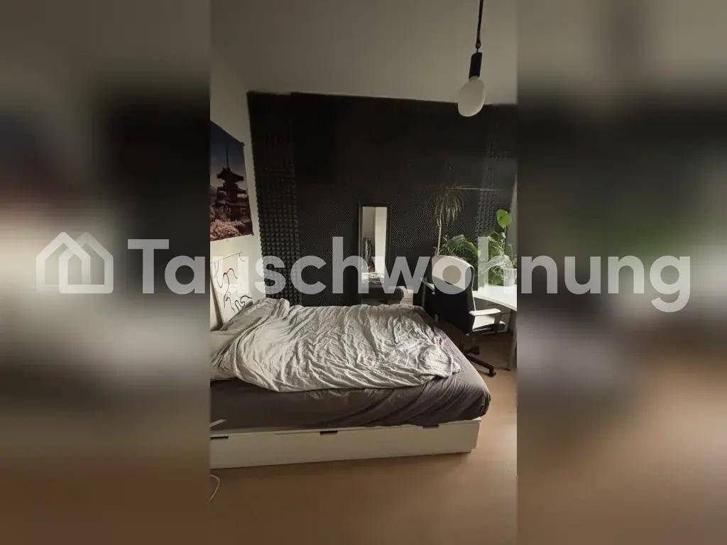 Schlafzimmer mit einem gemütlichen Bett und einem Arbeitsbereich an einer dunklen Wand.