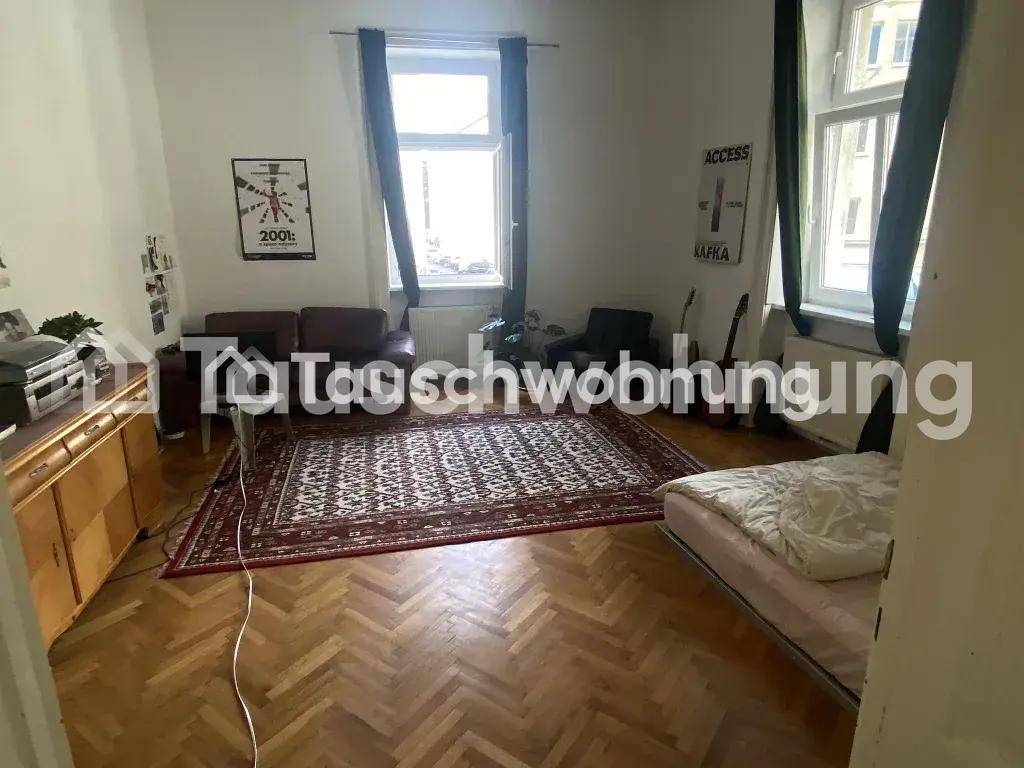 Geräumiges Wohnzimmer mit Fischgrätparkett, Teppich und zwei großen Fenstern.