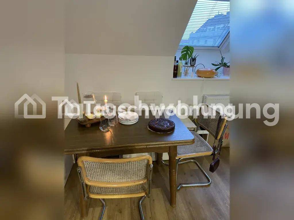 Essbereich mit Holztisch und Korbstühlen unter einem Dachfenster, gemütlich dekoriert.