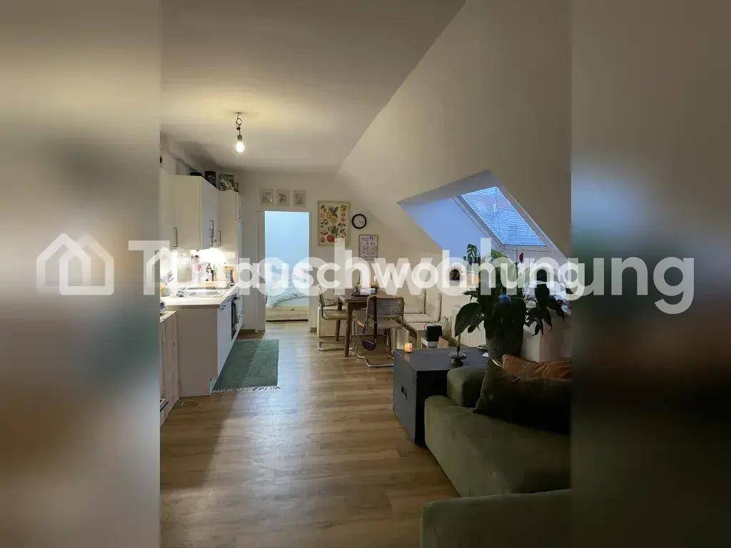Offener Wohnbereich mit integrierter Küche, Essbereich und Sofa, unter Dachschrägen gelegen.