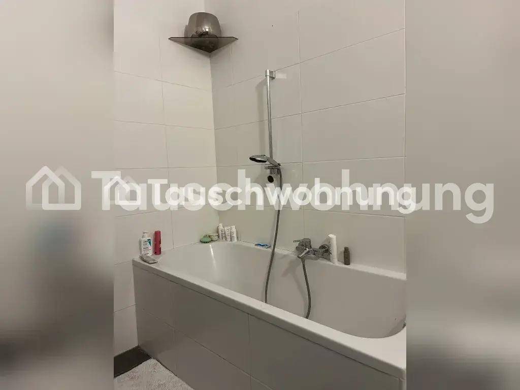 Badezimmer mit weiß gefliesten Wänden und einer Badewanne mit Duscharmatur.
