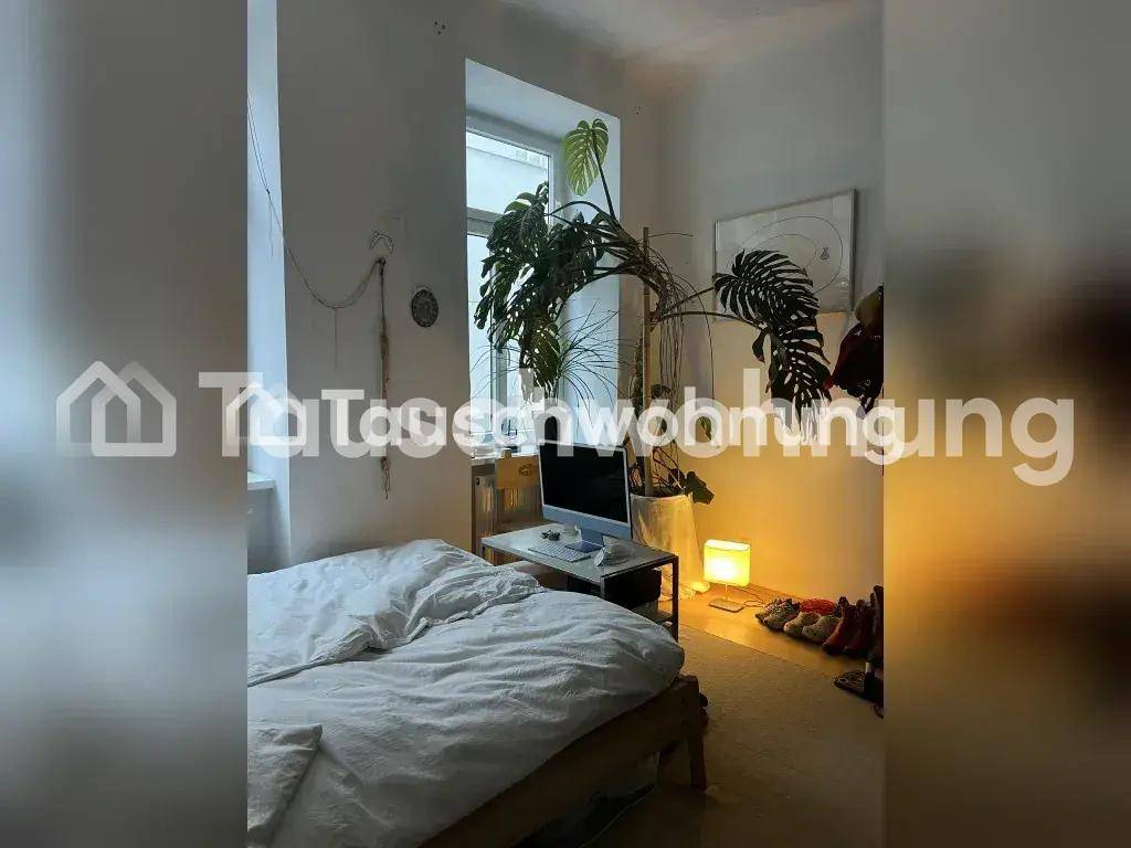 Helles Schlafzimmer mit Bett, Fenster und einer großen Zimmerpflanze.