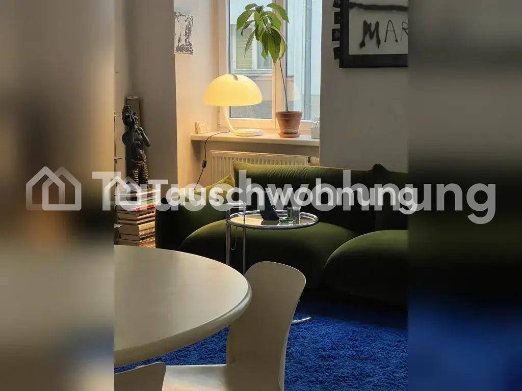 Gemütlicher Wohnbereich mit olivgrünem Sofa, Beistelltisch und Blick auf die Fenster.