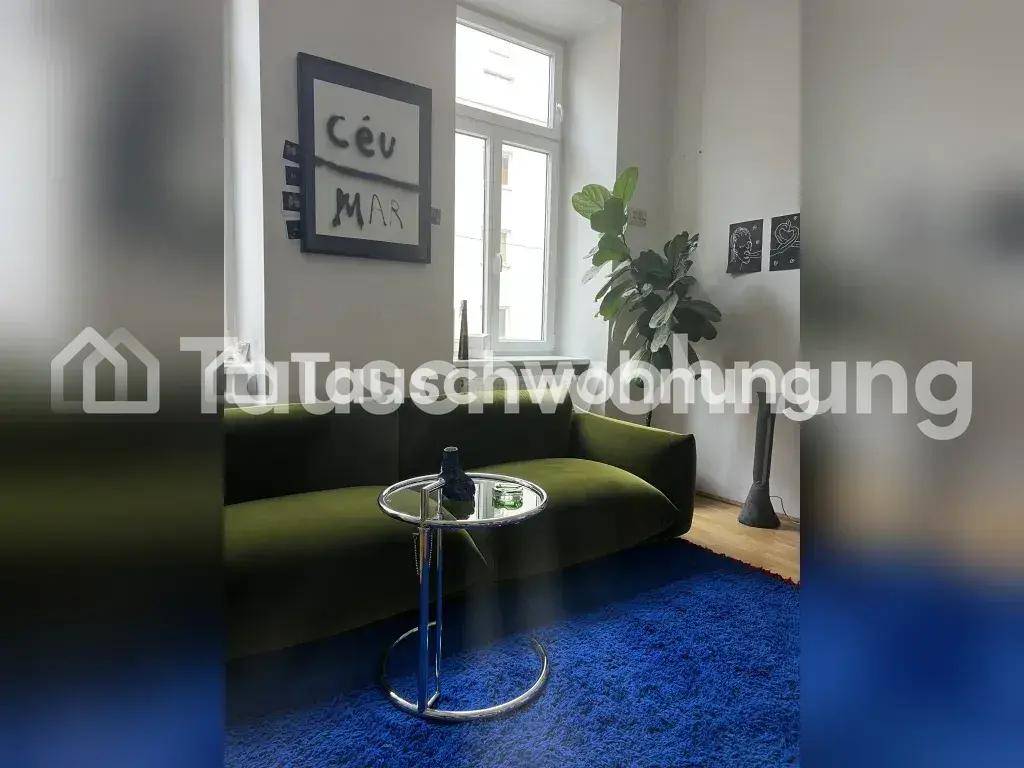 Wohnzimmer mit olivgrünem Sofa, blauem Teppich und hohen Fenstern, die viel Licht hereinlassen.