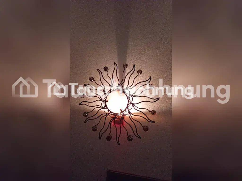 Dekorative Wandleuchte in Sonnenform mit funkelnden Kristallen an einer hellen Wand.