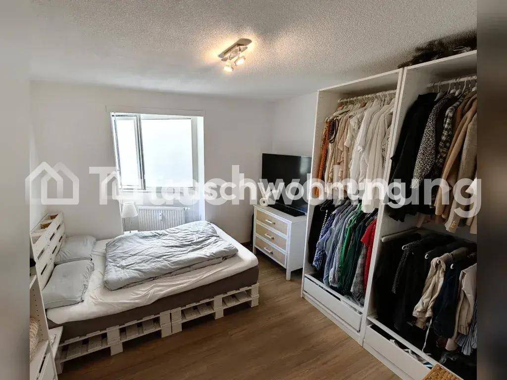 Schlafzimmer mit einem Bett aus Paletten und einem großen, offenen Kleiderschrank.