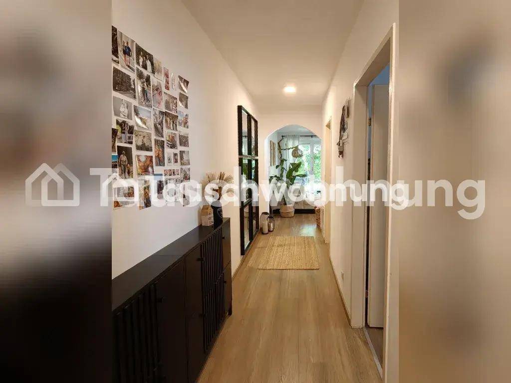 Langer, heller Flur mit Holzboden und einer Fotogalerie an der Wand.