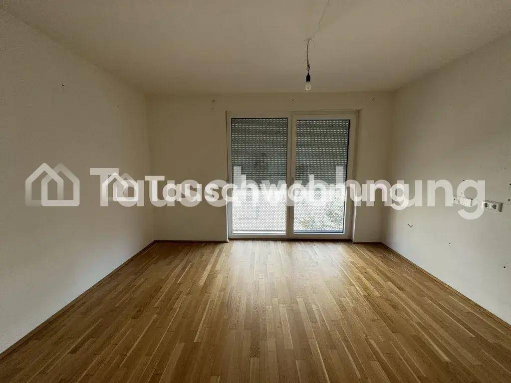 Geräumiger Raum mit Holzboden und großer Fensterfront, die den Zugang nach draußen ermöglicht.