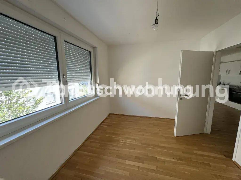 Heller Raum mit Holzboden und zwei Fenstern, die viel Tageslicht hereinlassen.