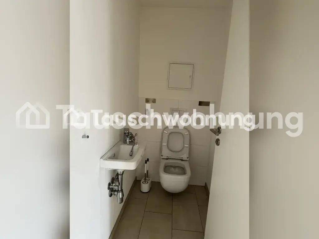 Praktisches Gäste-WC mit Toilette, kleinem Waschbecken und Fliesenboden.