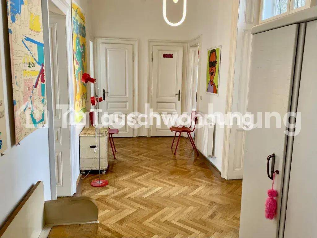 Heller Flur mit Fischgrätparkett, weißen Türen und farbenfroher moderner Kunst an den Wänden.