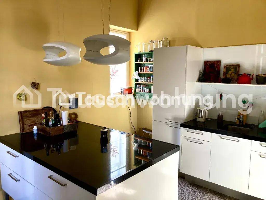 Moderne Küche mit weißen Schränken, schwarzen Arbeitsplatten, einer Kücheninsel und gelben Wänden.