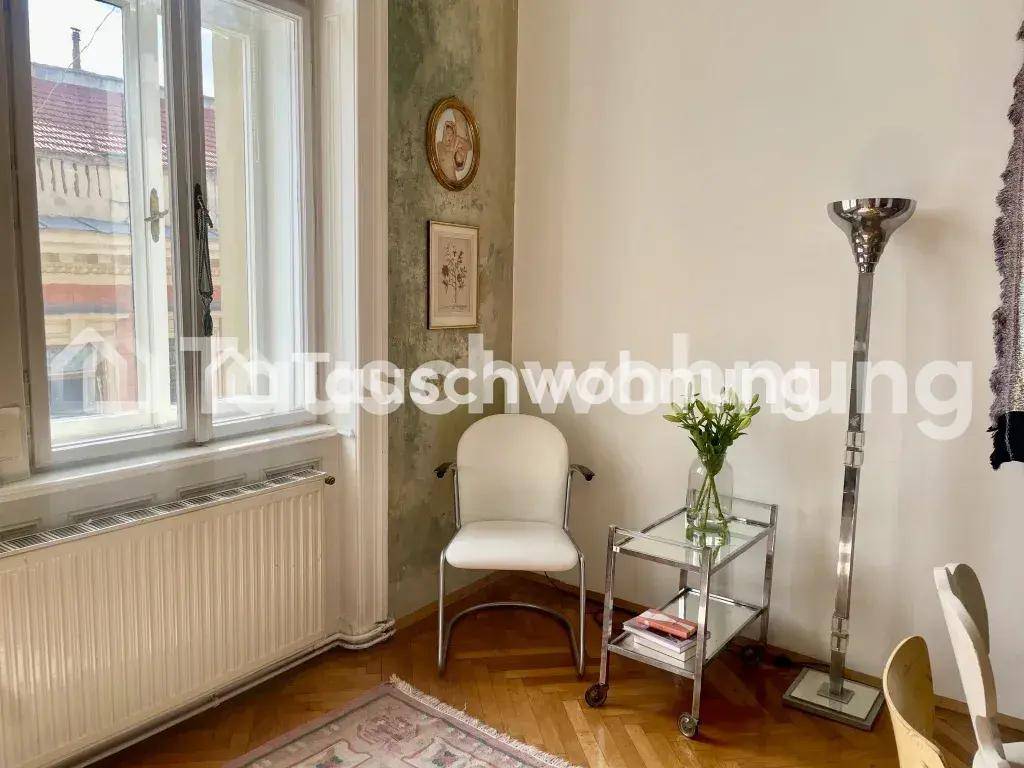Heller Raum mit Fenster, Heizkörper und einem Beistelltisch mit frischen Blumen.